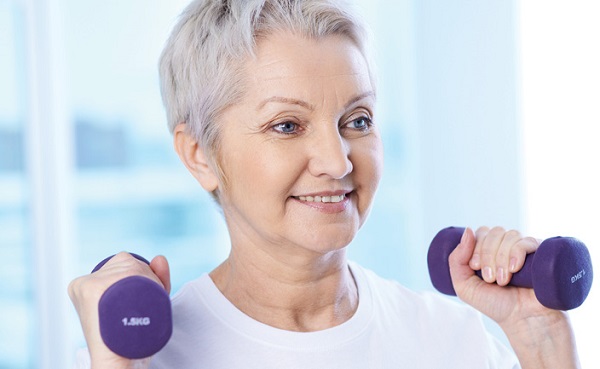 Older adult woman holding light weights in hands